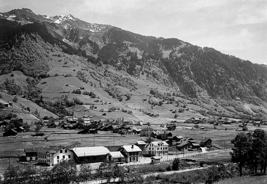 Bahnhof Engi-Vorderdorf: v. l. n. r. Stall, in dem sich die Batterieelemente zur Zusatzstromerzeugung befanden; Werkstatt und Maschinenhaus; Depot; Warendepot und Bahnhofgebäude; das kleine WC-Häuschen; Restaurant Bahnhof.